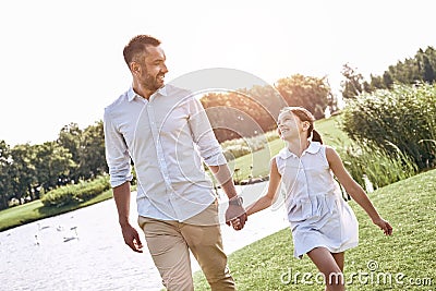 Single parent, Father and daughter walking on a grassy field hol Stock Photo