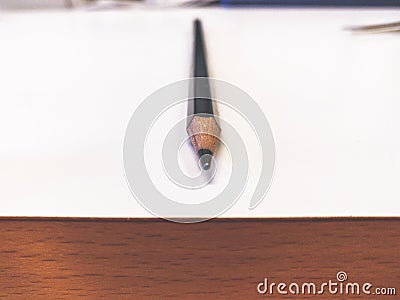 Single pencil on a white table with wooden side panel Stock Photo