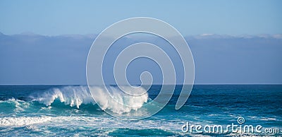 Single perfect wave in blue deep dangerous ocean - perfect barrel for brave surfers - coast in background for touristic scenic Stock Photo
