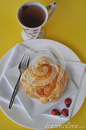 Single person breakfast of sweet pastry with fruit jam and a cup of hot tea on a colorful background Stock Photo