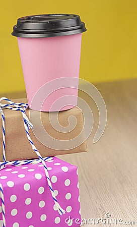 Single pink paper cup of coffee and heap gift boxes Stock Photo