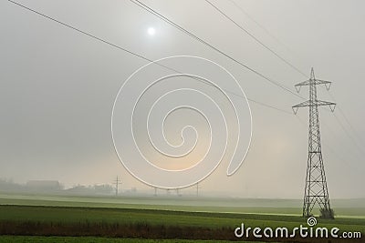 single power pole with dense fog and sun at the sky Stock Photo