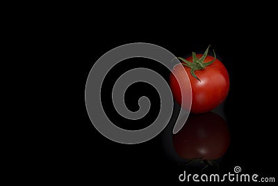 Single real tomatoe seen at its top on a black background with reflection Stock Photo