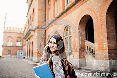 Single student walking and speak mobile phone with a university building in the background Stock Photo