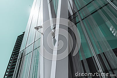A single surveillance camera on a facade of a contemporary business skyscraper on a sunny day, a security camera on a metal girder Stock Photo