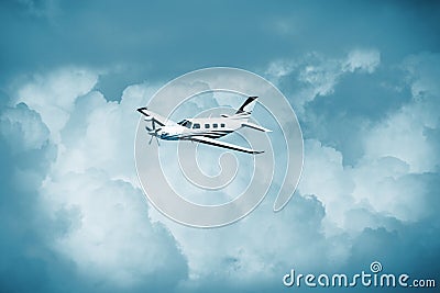 Single turboprop aircraft.. Small private plane flying in blue clouds. Stock Photo