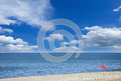 Single umbrella on the pebbly beach against the picturesque cloudy sky Stock Photo