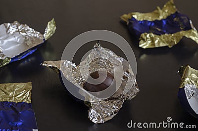 Single unwrapped chocolate bar among candy wrappers Stock Photo