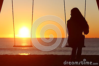 Single woman alone swinging on the beach Stock Photo