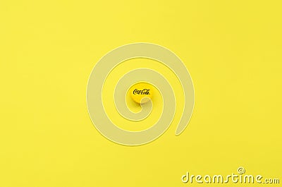 Single yellow bottle lid with Coca Cola logo on yellow background Editorial Stock Photo