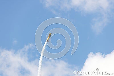 Yellow stunt plane climbing trailing a smoke contrail Editorial Stock Photo