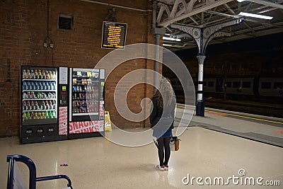 Singular young woman waits during the night at doncaster train station Editorial Stock Photo