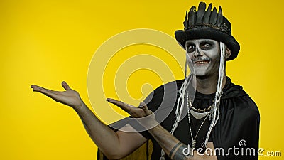 Sinister man with horrible Halloween skeleton makeup ooking at camera, pointing to the left Stock Photo