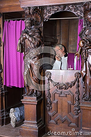 Sinner and priest in confession booth Stock Photo