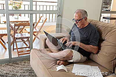 Sir typing on notebook, working at home in home office system in times of pandemic by Covid-19 virus. Lord works at home wearing Stock Photo