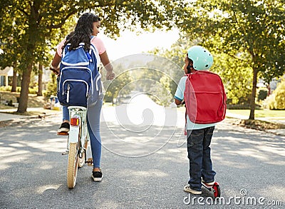 Sister With Brother Riding Scooter And Bike To School Stock Photo