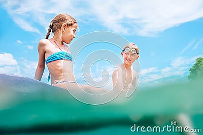 Sister and brother sitting on inflatable mattress and enjoying the sea water, have fun when swim in the sea. Careless childhood Stock Photo