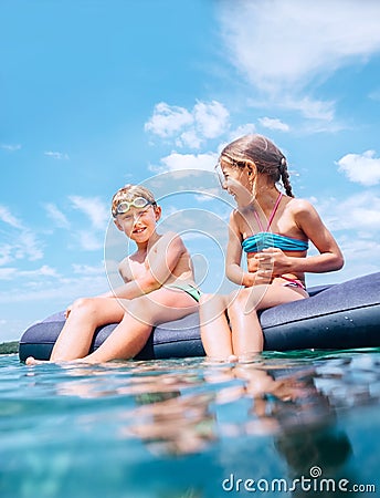 Sister and brother sitting on inflatable mattress and enjoying the sea water, have fun when swim in the sea. Careless childhood Stock Photo