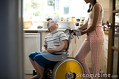 Sister helping her disabled brother in the kitchen Stock Photo