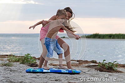 Sister teaching her brother how to surf Stock Photo
