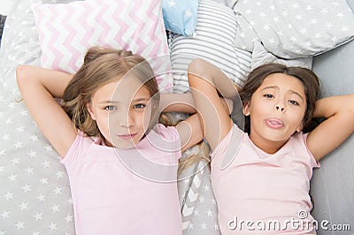 Sisterhood concept. Sharing secrets. Kids relaxing on bed. Sisters preparing sleep. Nice evening. Best friends. Children Stock Photo