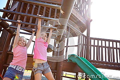 Sisters by blood, friends by choice. two little girls hanging on the monkey bars at the playground. Stock Photo