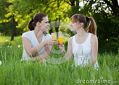 Sisters drinking orange juice in a park Stock Photo