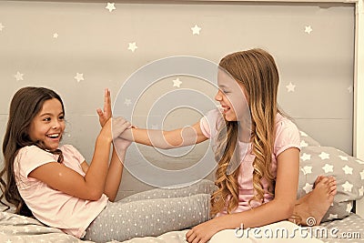 Sisters leisure. Girls in cute pajamas spend time together in bedroom. Sisters communicate while relax in bedroom Stock Photo