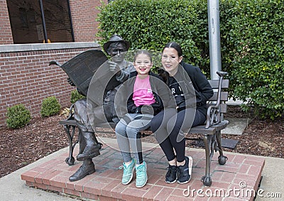 Sisters posing with bronze of Will Rogers on a bench, Claremore, Oklahoma Editorial Stock Photo