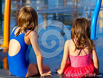 Sisters Sit at a Splash Pad Stock Photo