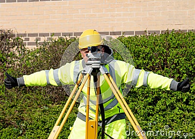 Site engineer doing level survey using auto level fitted on top of the wooden tripod and giving an ok sign Stock Photo