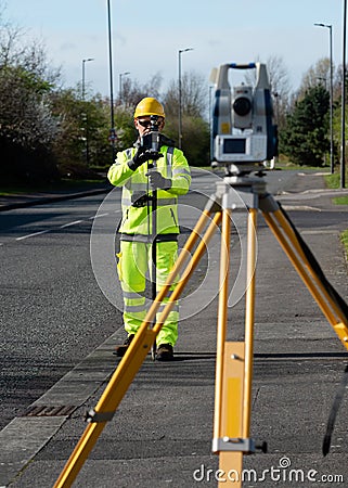 Site engineer doing road survey using modern robotic total station EDM before beginning of construction works Stock Photo