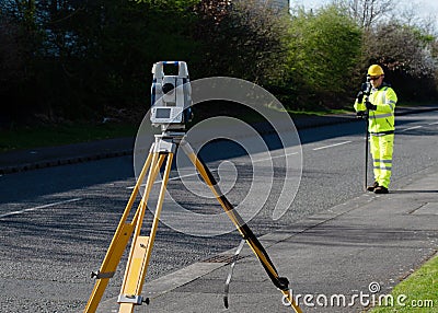 Site engineer doing road survey using modern robotic total station EDM before beginning of construction works Stock Photo