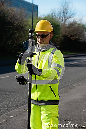 Site engineer doing road survey using modern robotic total station EDM before beginning of construction works Stock Photo