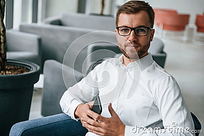 Sitting on the chair. Elegant man in formal clothes is indoors Stock Photo