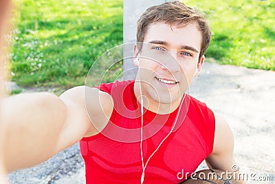 Sitting guy in a basketball court and take a selfie after match with friends - listen music with headphones. Stock Photo