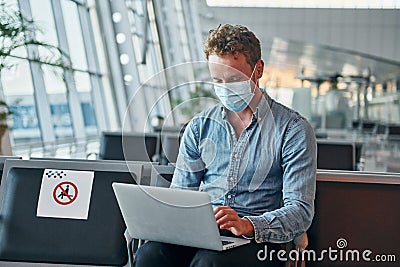 Sitting inside. Young man in formal wear is in modern airport. Conception of vacation Stock Photo