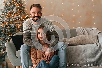 Sitting and looking forward. Lovely young couple are celebrating New Year at home Stock Photo