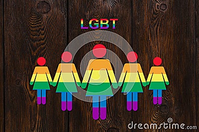 Six colored paper women on wooden background. Lgbt pride concept Stock Photo