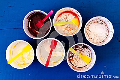 Six empty messy ice cream paper cups with yellow and red plastic Stock Photo