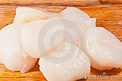 Six large, fresh, sea scallops on wood cutting board Stock Photo