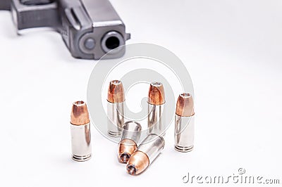 Six 9mm hollow point bullets in front of a black 9mm pistol Stock Photo