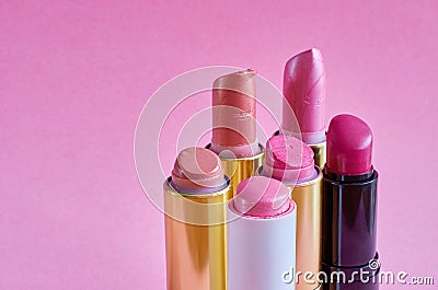 Six old used lipstick tubes stand on a pink background Stock Photo