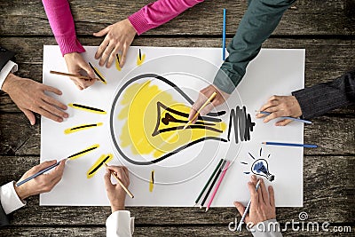 Six people, men and women, drawing bright yellow light bulb Stock Photo