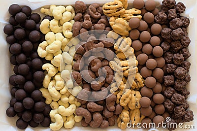 Six types of chocolate covered nuts in vertical rows Stock Photo