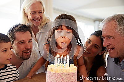Six year old white girl celebrating her birthday with family blowing out the candles on her cake Stock Photo