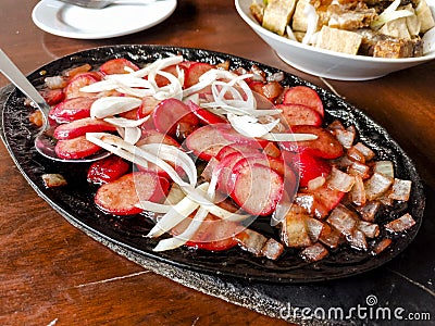 Sizzling Hotdog and onions, a popular Filipino appetizers or pulutan served in a restaurant or bar Stock Photo