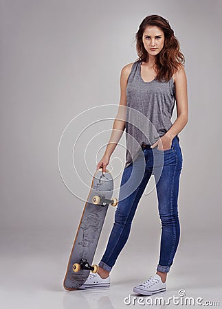 Skate betty. Full length studio portrait of casually-dressed young woman holding on a skateboard. Stock Photo