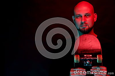 Skateboarder in black shirt with skateboard on neon light background Stock Photo