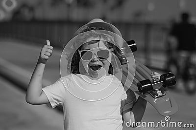 Skateboarder child boy in skate park. Kid boy with skateboard. Excited child with thumb up, street portrait close up Stock Photo